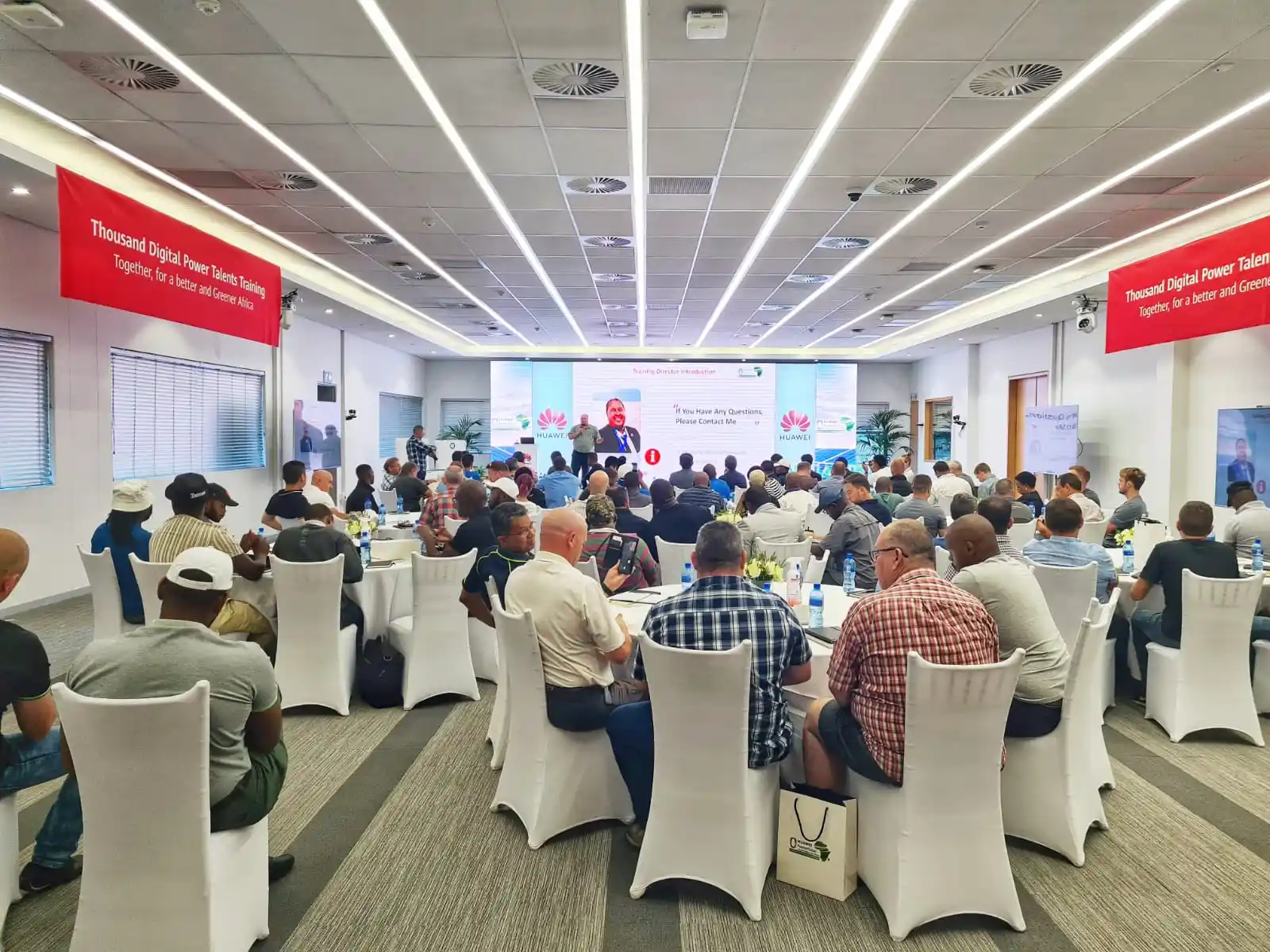 A room filled with people sitting and watching a presentation.